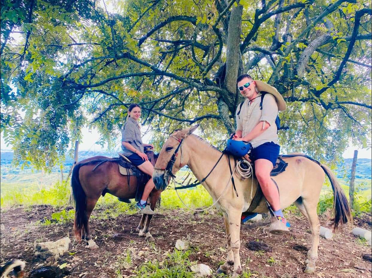 Pareja a caballo bajo un árbol durante la cabalgata